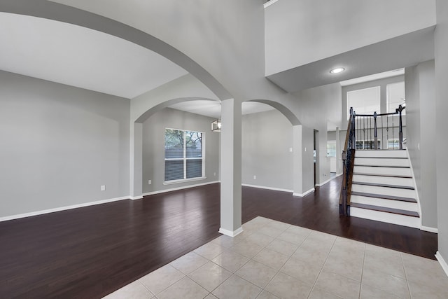 foyer entrance with arched walkways, stairs, baseboards, and wood finished floors