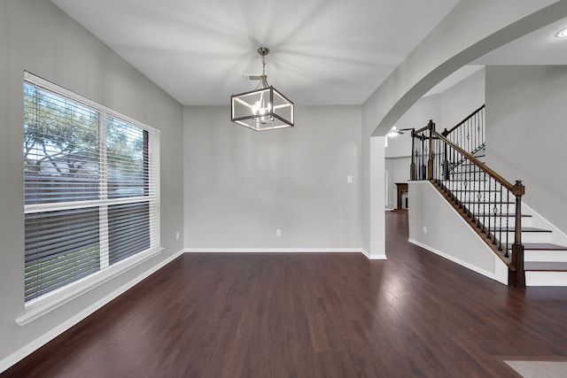 unfurnished dining area featuring stairs, wood finished floors, arched walkways, and baseboards