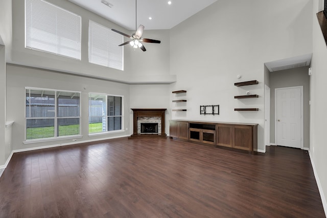 unfurnished living room with dark wood-style floors, a fireplace, baseboards, and ceiling fan