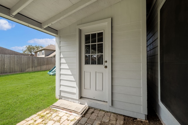 entrance to property featuring a lawn and fence