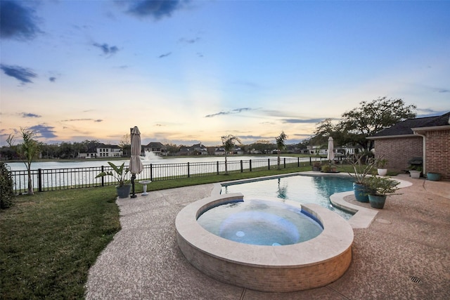 pool at dusk featuring an in ground hot tub, a yard, fence, and a patio area