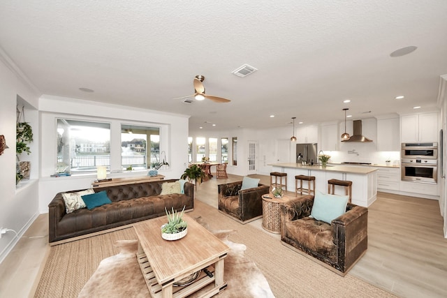 living area with light wood finished floors, visible vents, ornamental molding, recessed lighting, and a ceiling fan