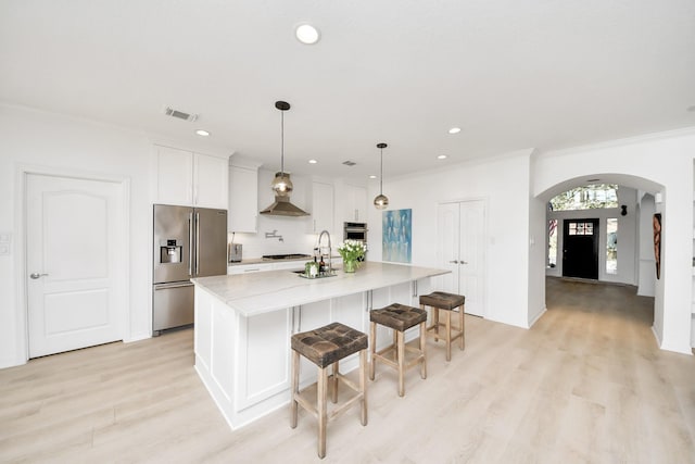 kitchen featuring visible vents, a large island, appliances with stainless steel finishes, arched walkways, and white cabinetry