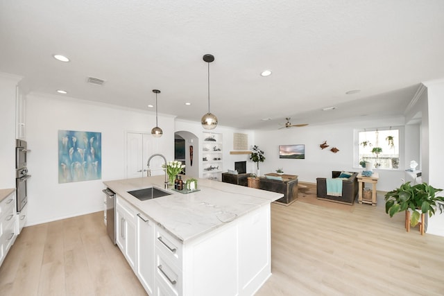 kitchen with visible vents, arched walkways, ceiling fan, stainless steel appliances, and a sink