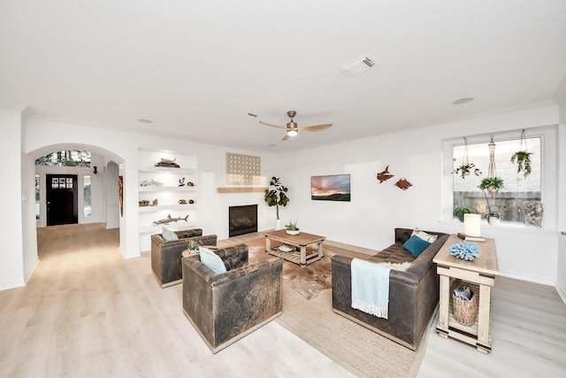 living room featuring visible vents, arched walkways, a healthy amount of sunlight, and a ceiling fan