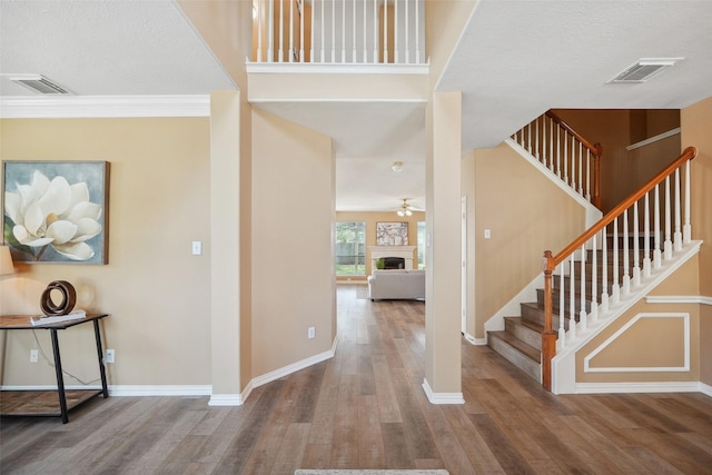 entryway with visible vents, a fireplace, baseboards, and wood finished floors