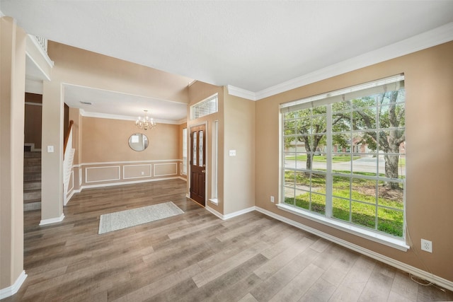 unfurnished room featuring stairway, wood finished floors, a chandelier, and crown molding