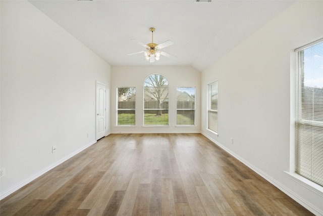 unfurnished room featuring baseboards, plenty of natural light, wood finished floors, and a ceiling fan