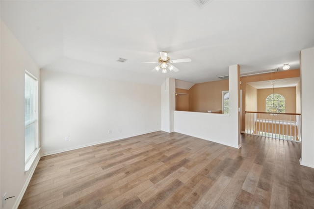 empty room with attic access, plenty of natural light, and wood finished floors