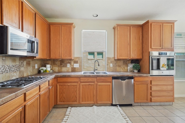 kitchen featuring light tile patterned floors, decorative backsplash, stainless steel appliances, and a sink