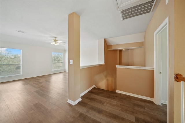 corridor featuring visible vents, baseboards, and dark wood finished floors