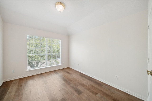 empty room with vaulted ceiling, wood finished floors, and baseboards