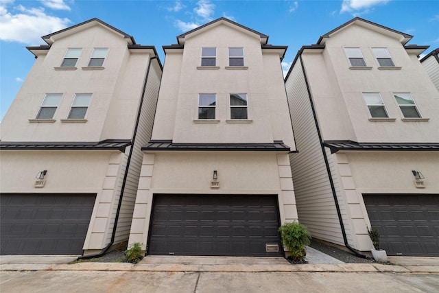 townhome / multi-family property with stucco siding, an attached garage, metal roof, and a standing seam roof