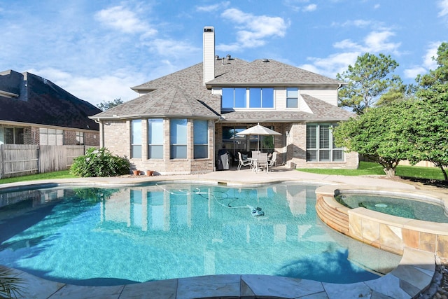 view of swimming pool with a patio area, fence, and a pool with connected hot tub