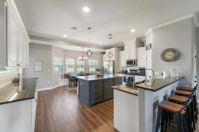 kitchen with dark countertops, visible vents, a sink, stainless steel appliances, and dark wood-style flooring