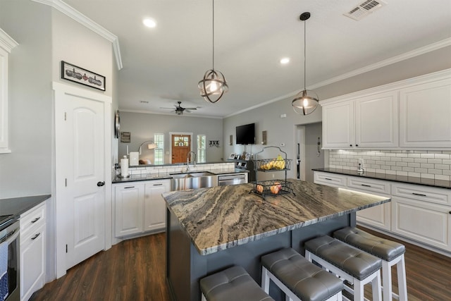 kitchen with visible vents, ornamental molding, decorative backsplash, a ceiling fan, and a sink