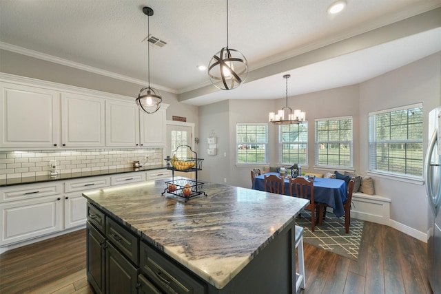 kitchen featuring visible vents, backsplash, a healthy amount of sunlight, dark wood finished floors, and white cabinets