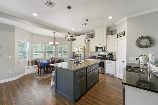 kitchen with a sink, tasteful backsplash, dark wood finished floors, white cabinetry, and appliances with stainless steel finishes