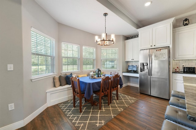 dining space featuring dark wood finished floors, an inviting chandelier, and baseboards