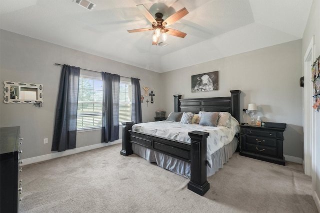 bedroom with light carpet, visible vents, a tray ceiling, and baseboards