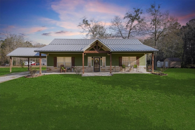 view of front of property with a storage unit, metal roof, a carport, and a front lawn