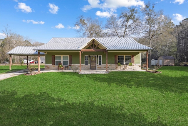 back of property with metal roof, a carport, a storage shed, and a lawn