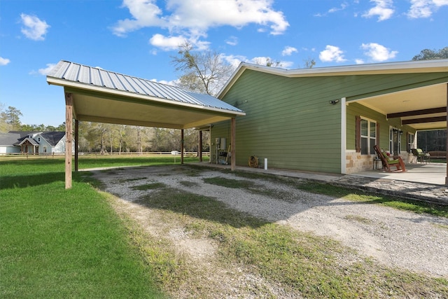 exterior space with a yard, metal roof, driveway, and a patio area