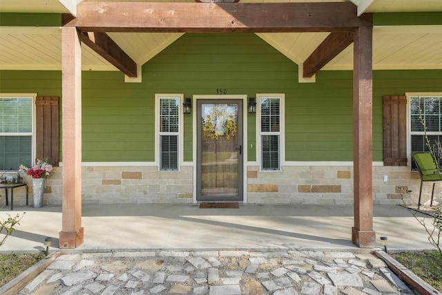 entrance to property with stone siding and a porch