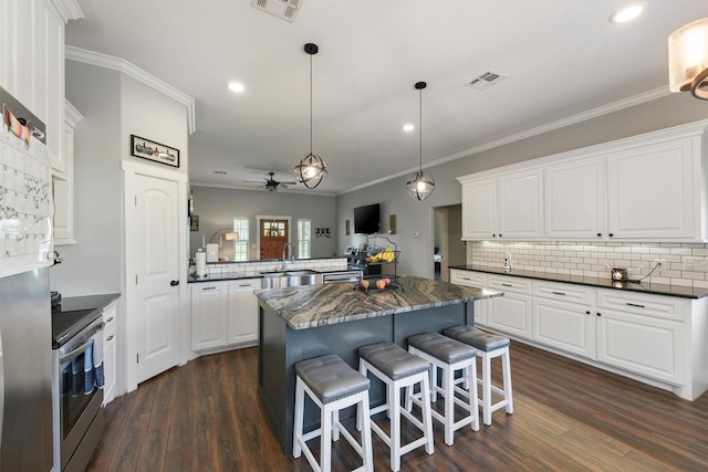 kitchen featuring visible vents, dark wood-type flooring, electric stove, a peninsula, and ceiling fan