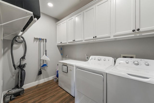 clothes washing area with cabinet space, washing machine and dryer, dark wood finished floors, and baseboards