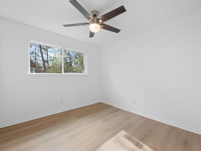 empty room with a ceiling fan, light wood-style floors, and baseboards