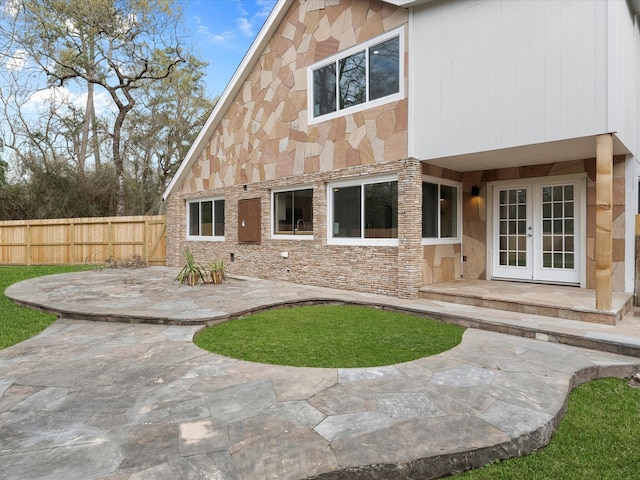 back of house with stone siding, french doors, and fence