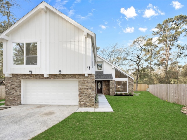 rear view of property with a lawn, concrete driveway, a garage, and fence