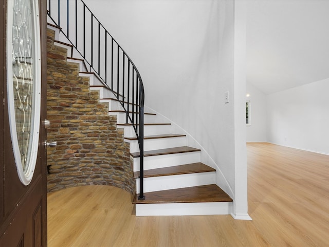 stairs featuring vaulted ceiling and wood finished floors