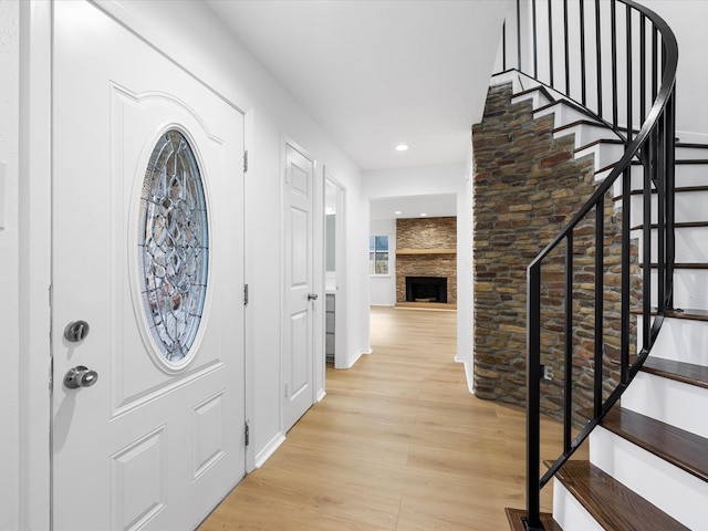 foyer entrance featuring stairs, light wood-style floors, recessed lighting, and a fireplace