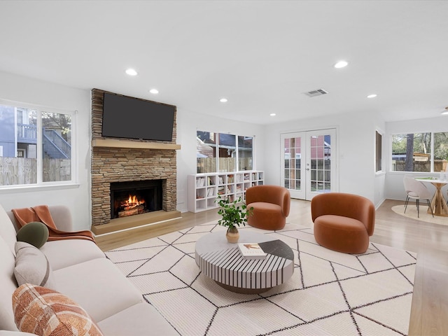 living room featuring visible vents, recessed lighting, french doors, a fireplace, and wood finished floors