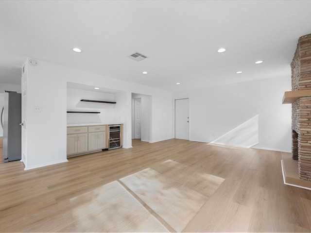 unfurnished living room with visible vents, wine cooler, light wood-type flooring, recessed lighting, and a fireplace