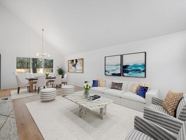 living room with high vaulted ceiling, an inviting chandelier, and wood finished floors