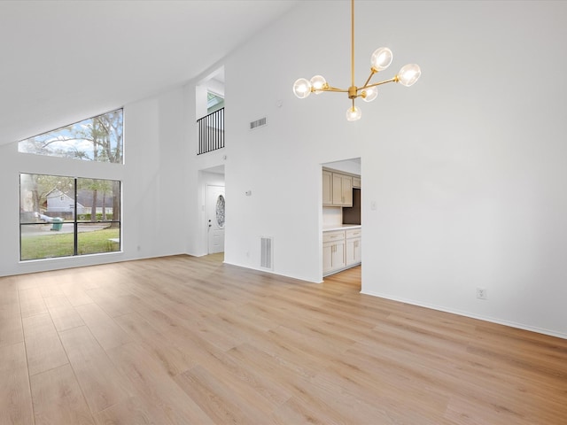 unfurnished living room featuring visible vents, an inviting chandelier, and light wood finished floors