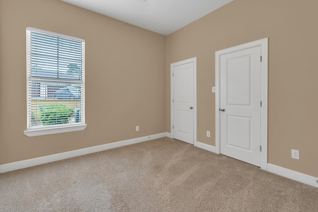 unfurnished bedroom featuring baseboards and light carpet