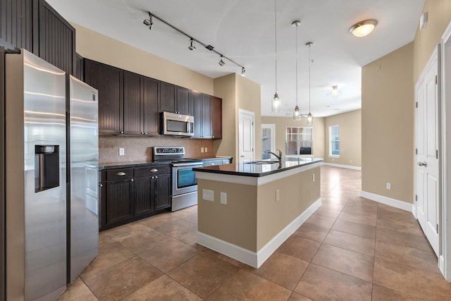 kitchen with tasteful backsplash, dark countertops, light tile patterned floors, stainless steel appliances, and a sink