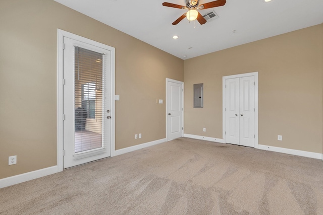 empty room with visible vents, electric panel, carpet, baseboards, and ceiling fan