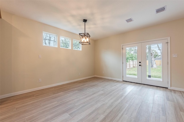 empty room with french doors, visible vents, a wealth of natural light, and light wood-type flooring