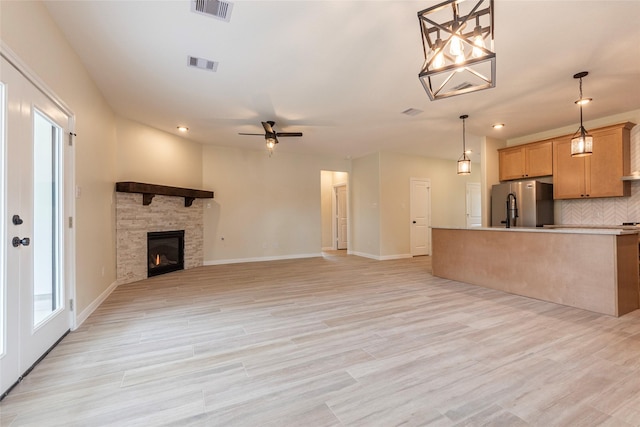 unfurnished living room featuring light wood-type flooring, visible vents, and ceiling fan