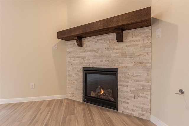 details with a stone fireplace, wood finished floors, and baseboards