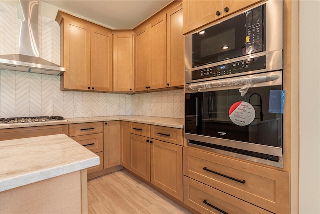 kitchen with decorative backsplash, stainless steel gas stovetop, black microwave, and wall chimney range hood