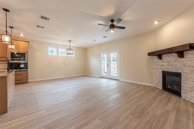 unfurnished living room with visible vents, light wood-style flooring, a fireplace, and ceiling fan