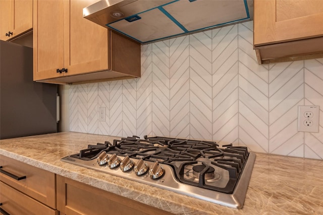 kitchen with stainless steel gas cooktop, backsplash, light countertops, and extractor fan