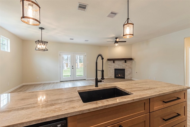 kitchen featuring light stone counters, visible vents, a wealth of natural light, and a sink