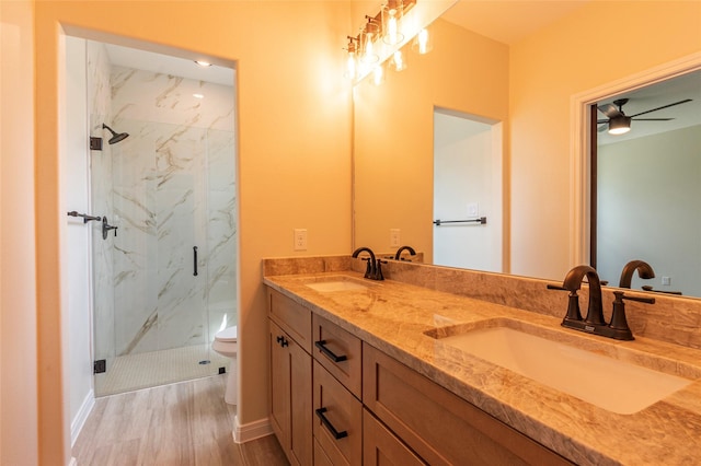 full bathroom with a sink, a marble finish shower, toilet, and wood finished floors